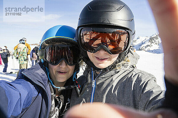 Boys wearing ski helmet and taking selfie on sunny day