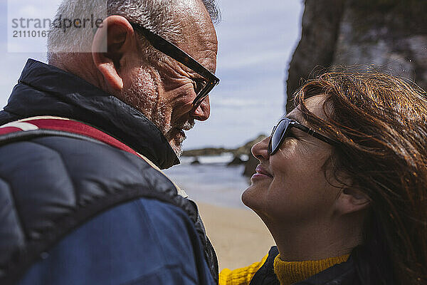 Smiling romantic senior couple in sunglasses at beach