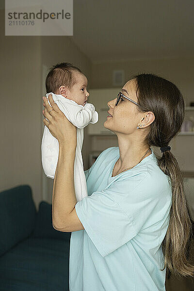 Mother lifting new born baby at home