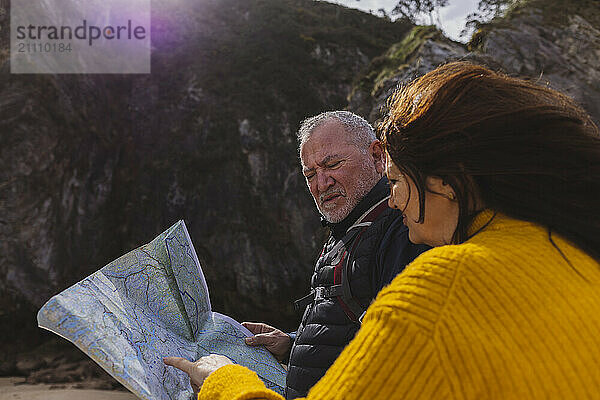 Senior couple searching direction on map at beach