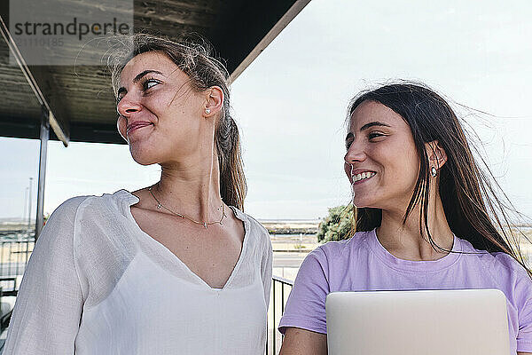 Portrait of two young women standing together on balcony