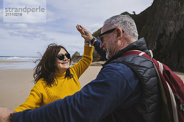 Happy couple holding hands and dancing on beach