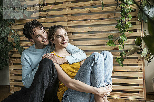 Young man embracing girlfriend sitting at home