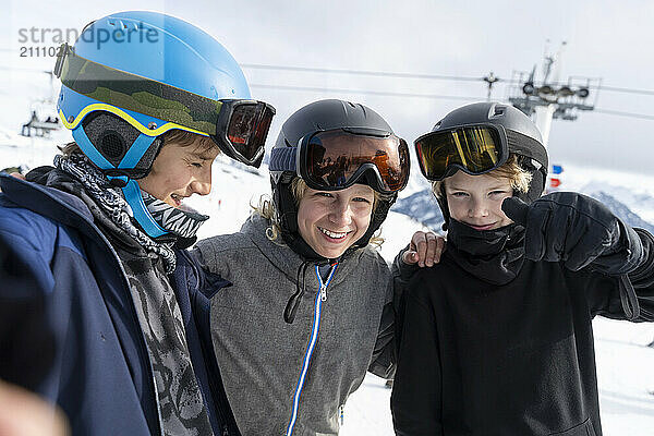 Happy boys wearing ski helmets and enjoying vacations in winter