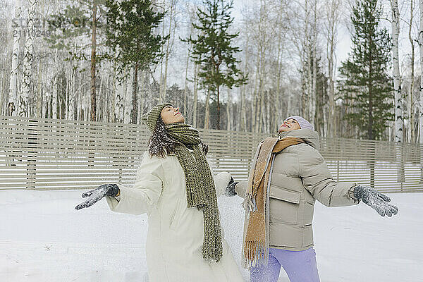 Happy friends spending leisure time enjoying on snow in winter