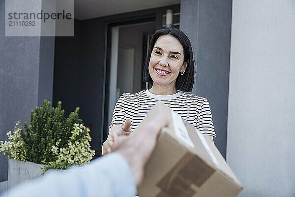 Woman wearing stripped T-shirt receiving package outside house