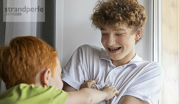 Happy boy playing with brother at home