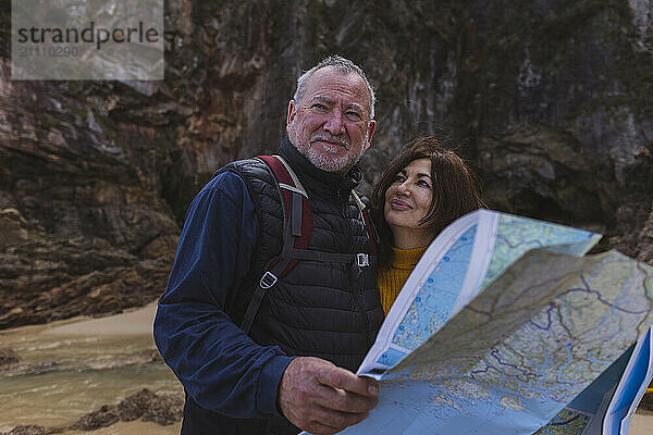 Romantic senior couple searching direction on map at beach