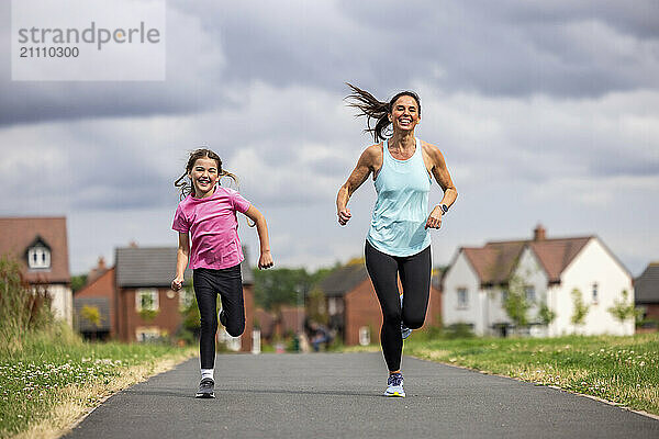 Cheerful woman running with daughter on footpath