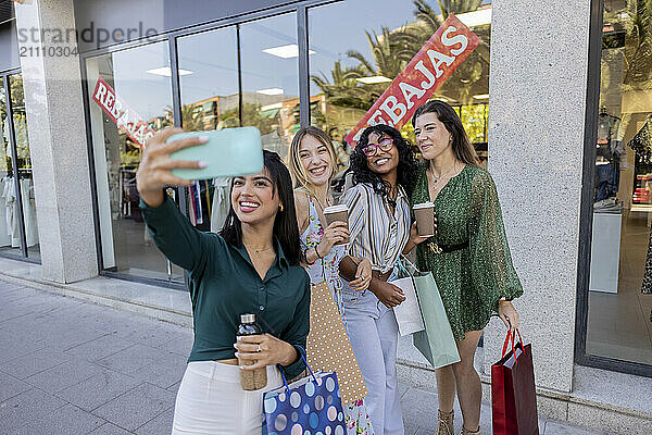 Young woman taking selfie with friends in street