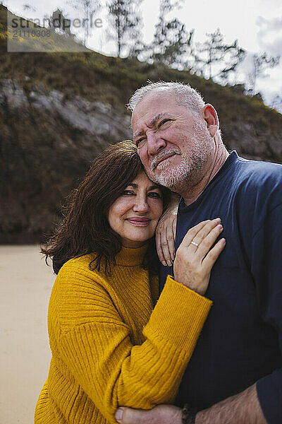 Smiling senior woman leaning on man at beach