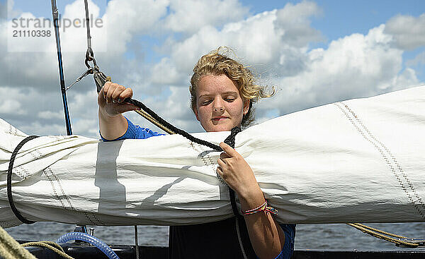 Girl fastening rope on boat in sea