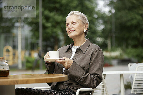 Thoughtful woman holding tea cup at outdoor cafe