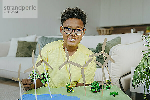 Happy boy sitting with solar energy school project in living room at home