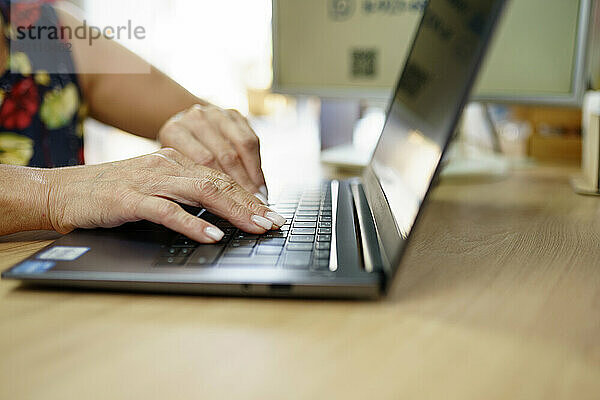 Hands of mature businesswoman using laptop on table