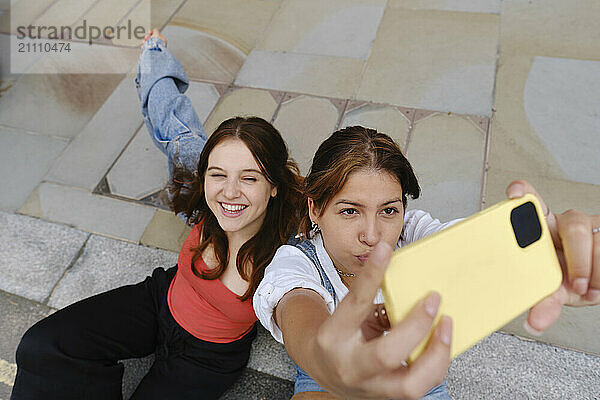 Happy gay couple taking selfie on footpath