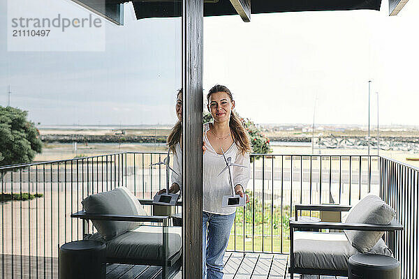 Portrait of pretty blonde standing on balcony with model of wind turbine in hands