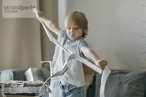 Boy with foil paper making astronaut suit in living room