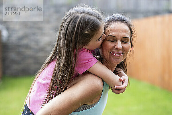 Daughter kissing mother in back yard