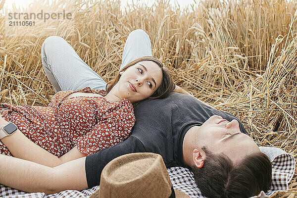 Affectionate woman lying with boyfriend on grass field