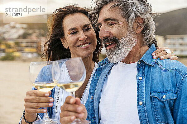 Happy couple toasting wineglasses at beach