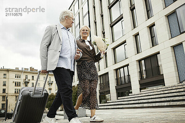 Senior couple walking near building in street