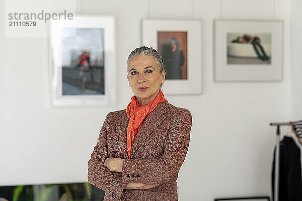 Senior woman with arms crossed standing in art museum