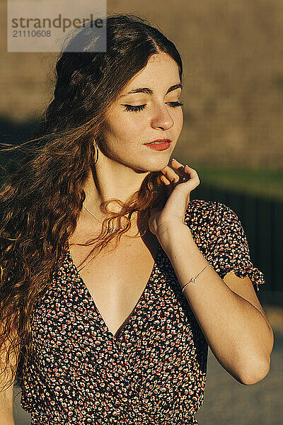 Young woman wearing patterned dress with hand in hair