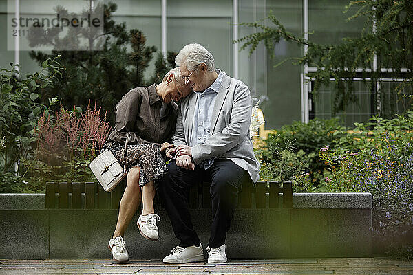 Affectionate couple sitting near building in street