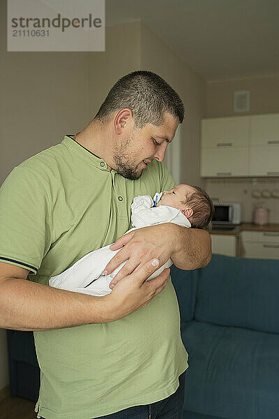 Smiling father carrying baby in arms at home