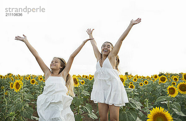 Sisters in white dress enjoying leisure time in sunflower field