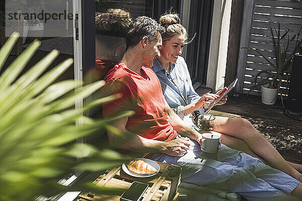 Couple relaxing on balcony with digital tablet