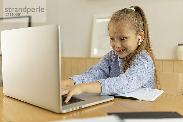 Smiling girl using laptop at home