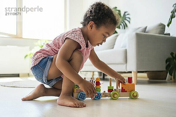 Girl playing with toy vehicle on floor at home