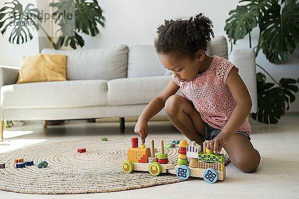 Girl stacking toy and moving vehicle at home