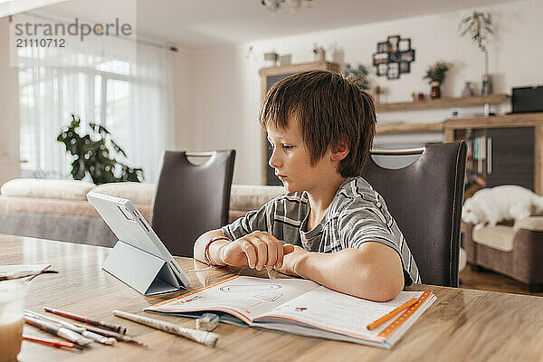 Boy studying near table using digital PC at home