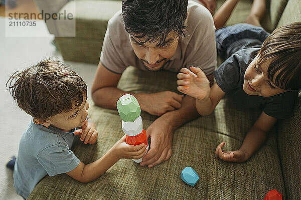 Boy building toy blocks with father and brother at home