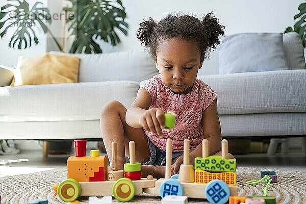 Girl playing with toys on rug at home