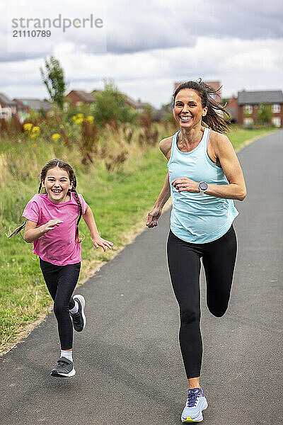 Mother and daughter in sportswear running on footpath