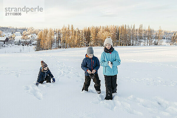 Siblings playing on snow in winter