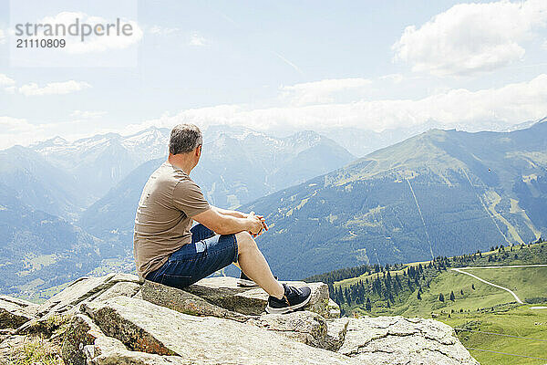 Man sitting on mountain and looking at view