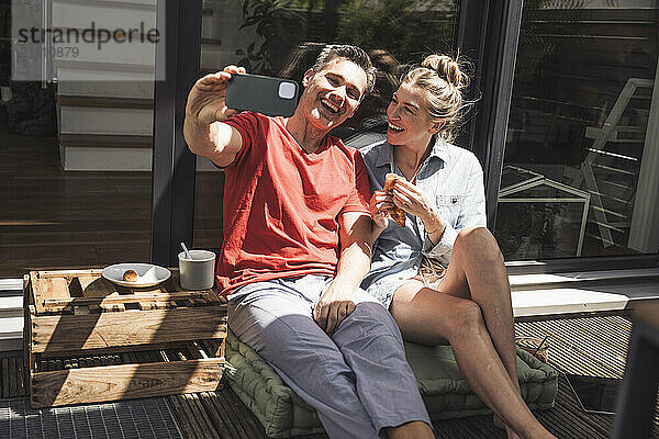 Couple taking selfie while relaxing on balcony