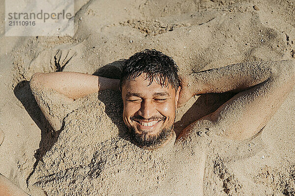 Smiling man covered in sand