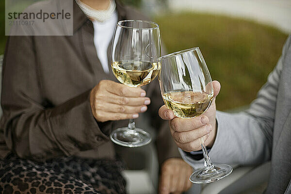 Hands of couple toasting with white wine