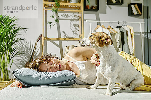 Woman lying near Jack Russell Terrier dog on bed at home