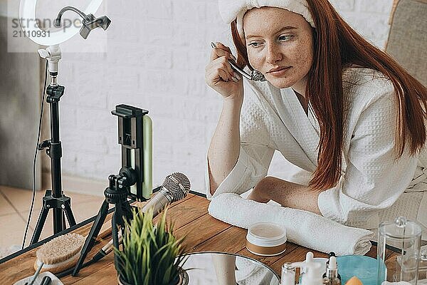 Caucasian female teenager creating beauty tutorial at home with makeup.