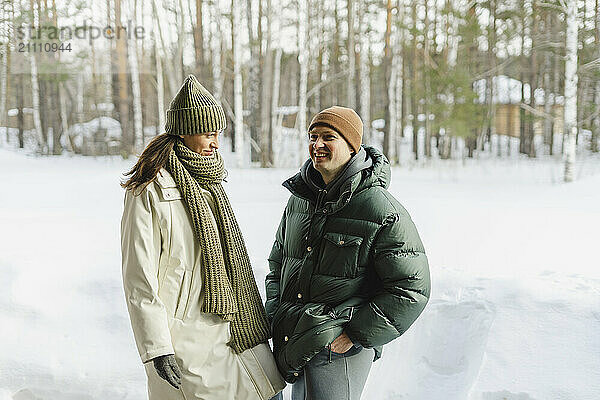 Happy couple in warm clothes standing on snow