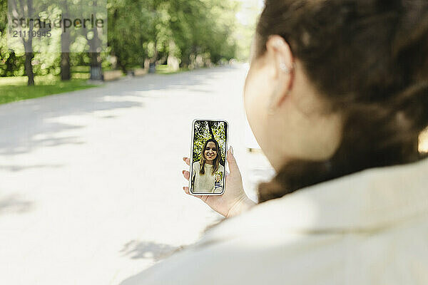 Woman video calling using smart phone at park