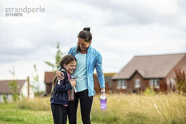 Woman holding water bottle and embracing daughter