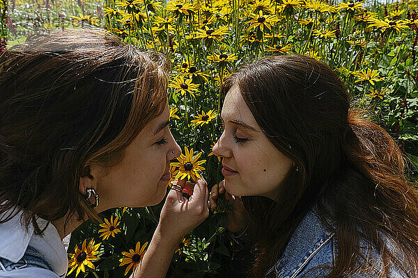 Gay couple with eyes closed smelling coneflower in garden